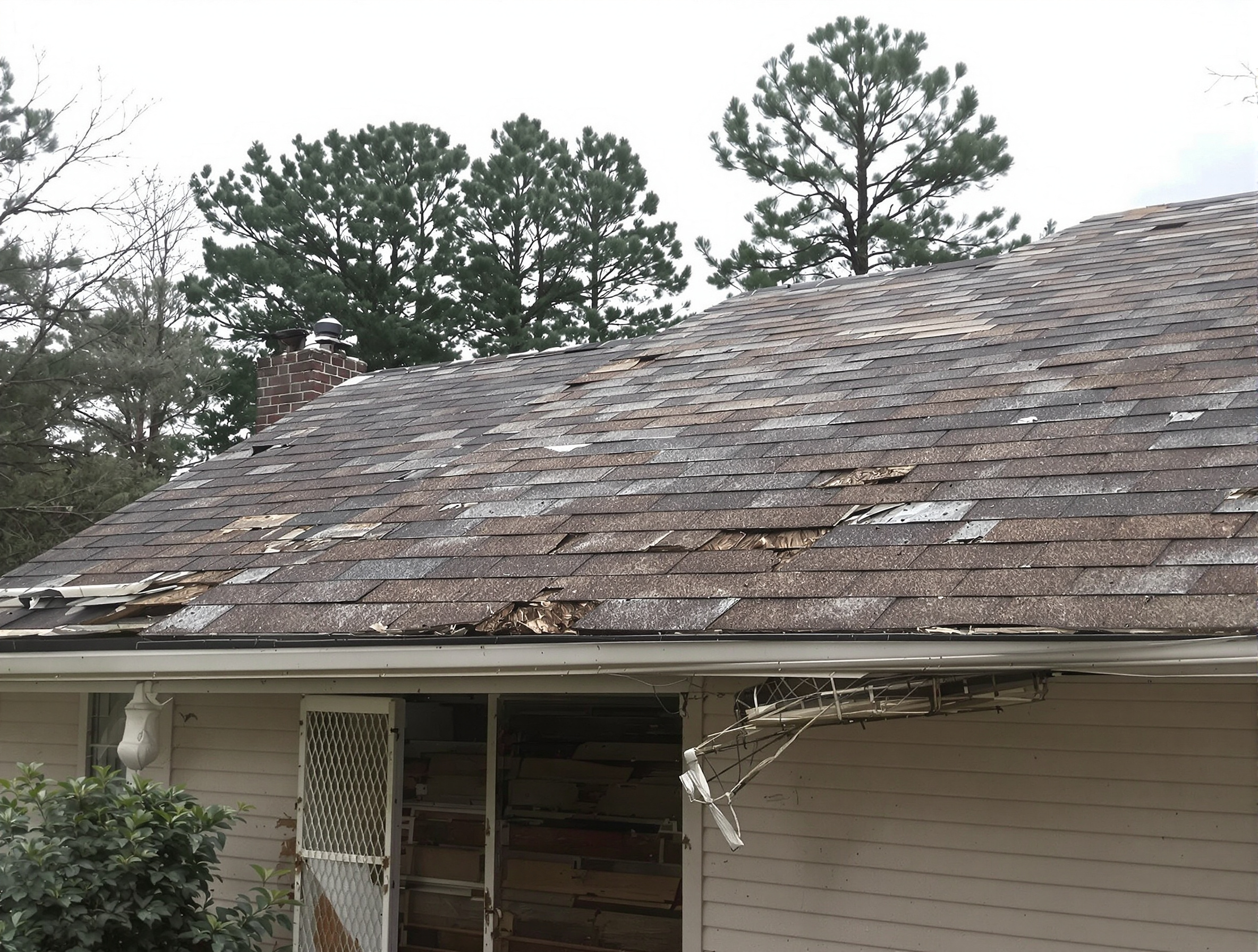 Small ranch home with severely deteriorated asphalt shingles and hanging gutter — before metal roof replacement in south Mississippi